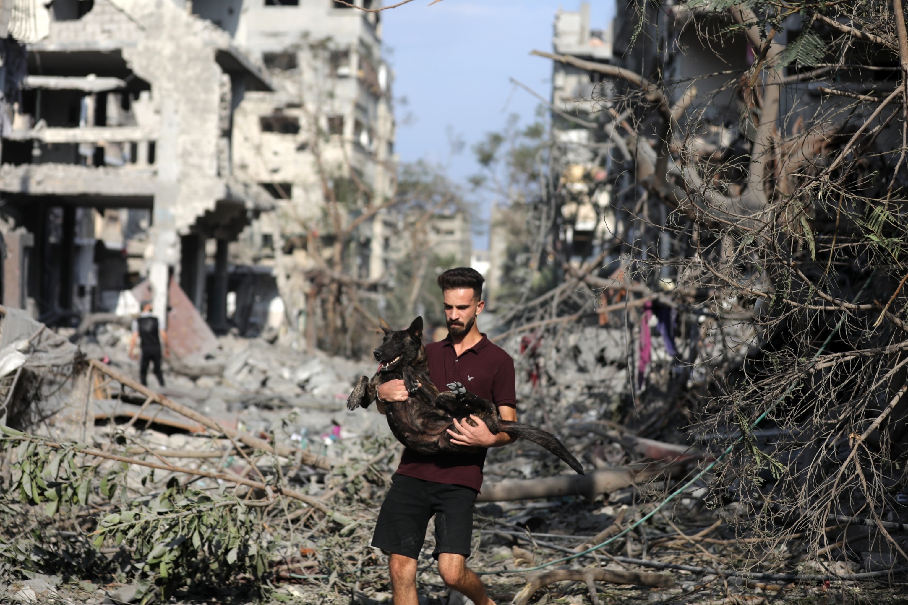 FOTO: En mann som bærer hunden sin når han forlater et bombet område etter israelske luftangrep natten over i Gaza by 11. oktober 2023.